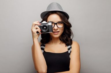 Beautiful attractive girl in a hat with camera.